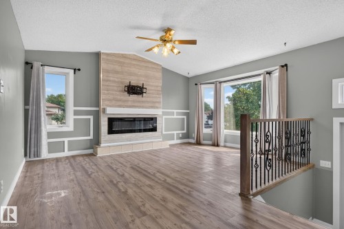 Spacious living area featuring a prominent fireplace with a light wood-finish surround, a modern linear firebox, and a tiled hearth - 9530 174 Avenue Nw, Edmonton, AB - Indoor Photo Showing Other Room With Fireplace