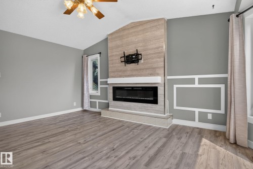 Living area featuring a floor-to-ceiling fireplace with an electric insert, wood-finish flooring, and vaulted ceiling - 9530 174 Avenue Nw, Edmonton, AB - Indoor Photo Showing Living Room With Fireplace