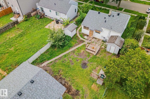 Expansive lot featuring a residential structure with a shingled roof, a wooden deck, and two detached storage sheds - 11935 125 Street Nw, Edmonton, AB 