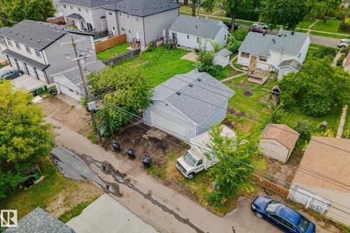 Rear property featuring a detached garage, expansive grassy area, and two storage sheds - 11935 125 Street Nw, Edmonton, AB 