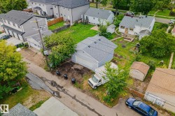 Rear property featuring a detached garage, expansive grassy area, and two storage sheds - 