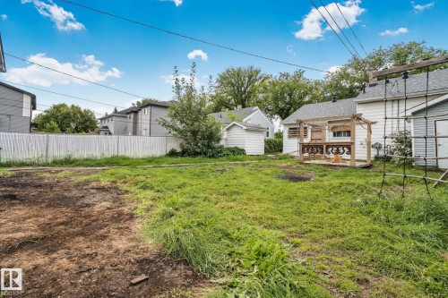 Expansive backyard featuring a wood deck with pergola, mature trees, and a detached shed - 11935 125 Street Nw, Edmonton, AB 