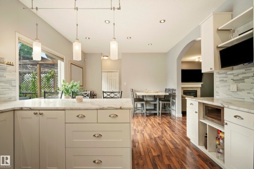 White cabinetry, light-toned countertops, tile backsplash, wood-finish flooring, and recessed lighting - 1660 Tomlinson Common Nw, Edmonton, AB 