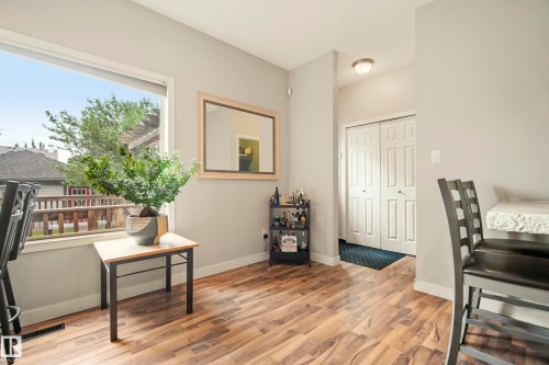 Expansive window with white trim, wood-finish flooring, light gray wall paint, and white paneled bi-fold closet doors - 1660 Tomlinson Common Nw, Edmonton, AB 