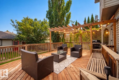 Expansive wood-finish deck with a built-in pergola, privacy lattice, and integrated bench seating - 1660 Tomlinson Common Nw, Edmonton, AB 
