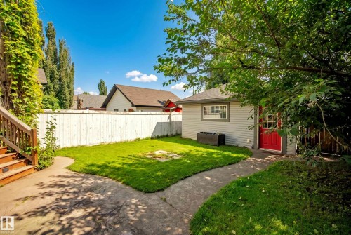 Expansive backyard featuring a manicured lawn, concrete pathway, and a privacy fence - 1660 Tomlinson Common Nw, Edmonton, AB 