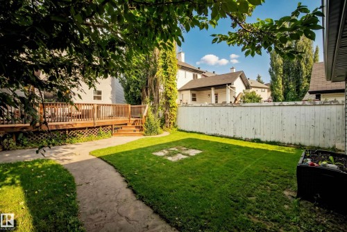 Expansive backyard featuring a wood deck with railings, integrated steps, a manicured lawn, and a paved pathway - 1660 Tomlinson Common Nw, Edmonton, AB 