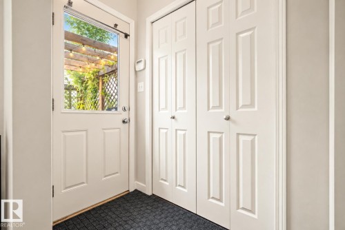 Entryway with a glass-paneled door, two panel-style bi-fold closets, and light-toned walls - 1660 Tomlinson Common Nw, Edmonton, AB 