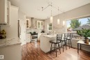 Kitchen featuring stainless steel appliances, wood-finish flooring, white cabinetry, a large window, and recessed lighting - 1660 Tomlinson Common Nw, Edmonton, AB 