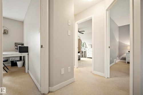 Carpeted hallway providing access to multiple rooms with neutral wall colors and white trim - 1660 Tomlinson Common Nw, Edmonton, AB 