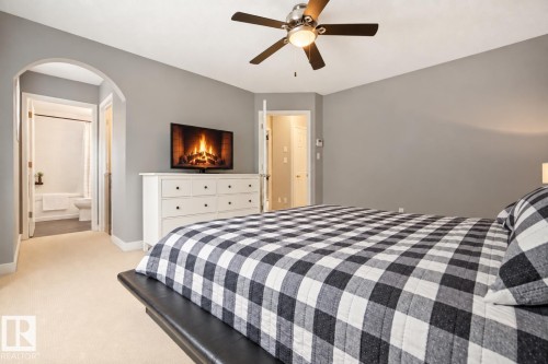 Neutral tone wall finish, ceiling fan with integrated lighting, carpet flooring, arched doorway, and built-in closet - 1660 Tomlinson Common Nw, Edmonton, AB 