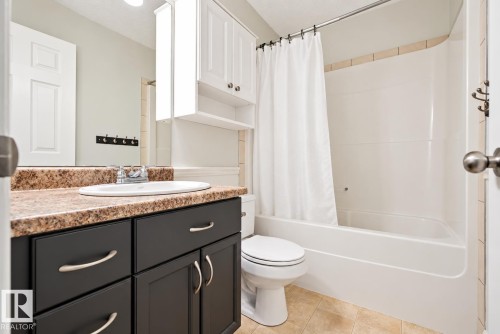 Vanity with dark wood cabinetry and a stone-finish countertop - 1660 Tomlinson Common Nw, Edmonton, AB 