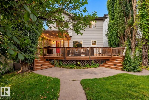 Expansive wood deck with a built-in pergola, two sets of stairs, and decorative lattice skirting - 1660 Tomlinson Common Nw, Edmonton, AB 