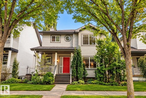 Two-story residence with light gray siding, a covered front porch, and a red entry door - 1660 Tomlinson Common Nw, Edmonton, AB 