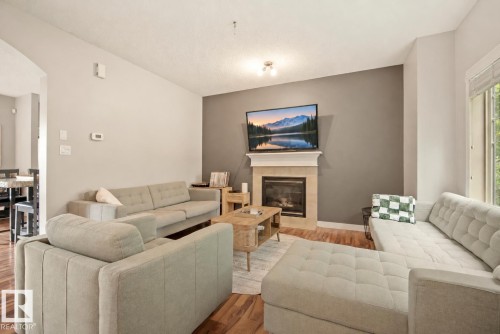 Hardwood flooring, natural light, gas fireplace with mantel, recessed ceiling lighting, and an open concept layout - 1660 Tomlinson Common Nw, Edmonton, AB 