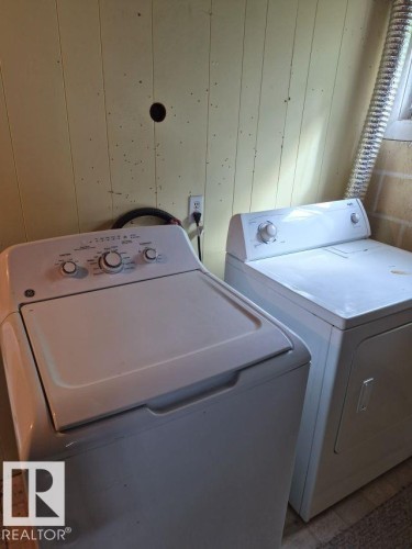Dedicated laundry area featuring a white washing machine and dryer, paneled walls, and a window - 12005 45 Street Nw, Edmonton, AB 