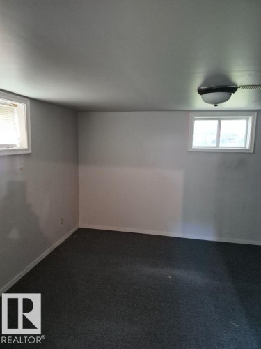 Room featuring gray carpeting, light gray walls, a flush-mount ceiling light fixture, and two windows with white trim - 12005 45 Street Nw, Edmonton, AB 