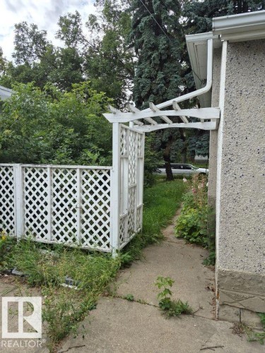 Lattice fencing with an arched arbor entry and concrete pathway - 12005 45 Street Nw, Edmonton, AB 