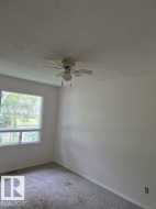 Neutral wall finishes, window with exterior scenery, and a ceiling fan with integrated lighting - 