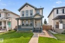 Gable roofline, covered front porch, light-colored siding, dark trim windows, and a brick-paved side walkway - 8923 173 Avenue Nw, Edmonton, AB 