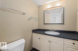 Cream cabinetry with dark countertop, undermount sink with chrome faucet, framed mirror, and chrome light fixture - 