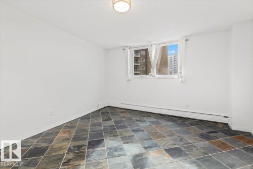 Multi-toned floor tiles, white walls, and a window with natural light - #702 10045 117 St Nw, Edmonton, AB 