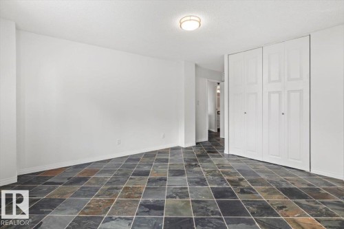 Multi-toned square tile flooring, built-in bi-fold closet doors, and flush-mount ceiling lighting - #702 10045 117 St Nw, Edmonton, AB 