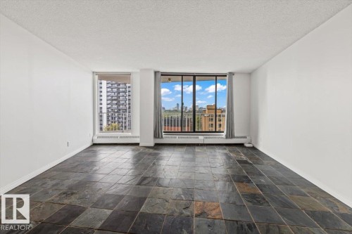 Expansive room featuring large format slate tile flooring, white painted walls, and abundant natural light through multiple windows - #702 10045 117 St Nw, Edmonton, AB 