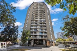 High-rise concrete building with multiple private balconies, featuring a ground-level entrance and mature perimeter landscaping - 
