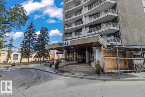 Concrete high-rise exterior with multiple levels of balconies, covered entrance, and a curved concrete driveway - #702 10045 117 St Nw, Edmonton, AB 