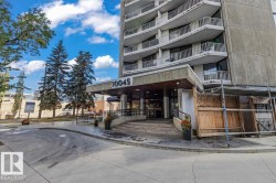 Concrete high-rise exterior with multiple levels of balconies, covered entrance, and a curved concrete driveway - 