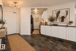 Entryway with multi-toned tile flooring, built-in storage cabinetry, brushed nickel light fixture, and a kitchen area featuring recessed lighting and integrated appliances VIRTUAL STAGING - 