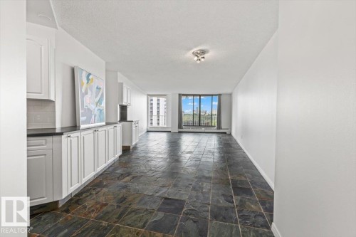 Slate-look tile flooring, white cabinetry, dark countertops, tile backsplash, and expansive windows - #702 10045 117 St Nw, Edmonton, AB 