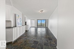 Slate-look tile flooring, white cabinetry, dark countertops, tile backsplash, and expansive windows - 