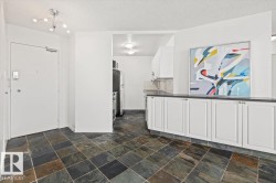 Multi-tone tile flooring, white cabinetry with dark countertops, and a modern ceiling light fixture - 