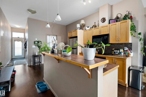 Kitchen area featuring dark wood-finish flooring, light-toned cabinetry, and a peninsula counter with a contrasting surface - #713 10503 98 Av Nw, Edmonton, AB - Indoor