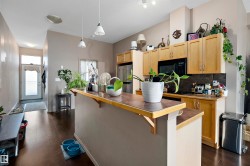 Kitchen area featuring dark wood-finish flooring, light-toned cabinetry, and a peninsula counter with a contrasting surface - 