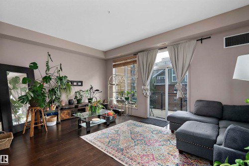 Spacious living area featuring dark wood-finish flooring and a private outdoor balcony - #713 10503 98 Av Nw, Edmonton, AB - Indoor Photo Showing Living Room
