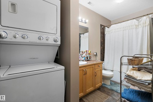 Compact laundry area featuring a stacked washer and dryer unit - #713 10503 98 Av Nw, Edmonton, AB - Indoor Photo Showing Laundry Room