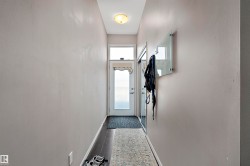 Entryway featuring a white door with upper window, dark wood-finish flooring, light grey painted walls, and a ceiling-mounted light fixture - 