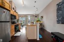 Open-concept kitchen featuring wood cabinetry, stainless steel refrigerator, and integrated appliances - #713 10503 98 Av Nw, Edmonton, AB  - Indoor Photo Showing Kitchen 