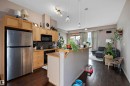Open-concept kitchen featuring light wood cabinetry, stainless steel appliances, dark wood-finish flooring, and a breakfast bar with pendant lighting - #713 10503 98 Av Nw, Edmonton, AB  - Indoor Photo Showing Kitchen 