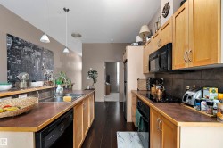 Contemporary kitchen with dark wood-finish flooring, light wood cabinetry, and contrasting dark countertops - 