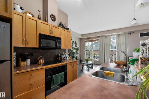Kitchen featuring wood-finish cabinetry, stainless steel appliances, and a double basin sink - #713 10503 98 Av Nw, Edmonton, AB - Indoor Photo Showing Kitchen With Double Sink