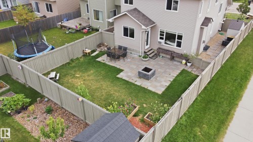 Fenced backyard featuring a paver patio with a built-in fire pit, a wooden shed, and raised garden beds - 1564 36 Avenue Nw, Edmonton, AB 