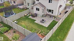 Fenced backyard featuring a paver patio with a built-in fire pit, a wooden shed, and raised garden beds - 