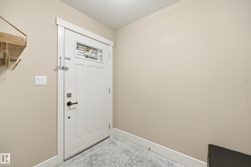 White paneled door with decorative glass inlay, black hardware, and white trim - 1564 36 Avenue Nw, Edmonton, AB 