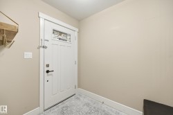 White paneled door with decorative glass inlay, black hardware, and white trim - 
