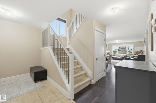 Staircase featuring carpeted treads, white risers, and an iron baluster railing - 1564 36 Avenue Nw, Edmonton, AB 