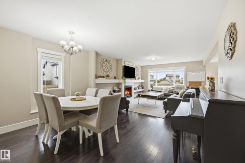 Open-concept living area with dark wood-finish flooring, a built-in fireplace, and a large window - 1564 36 Avenue Nw, Edmonton, AB 